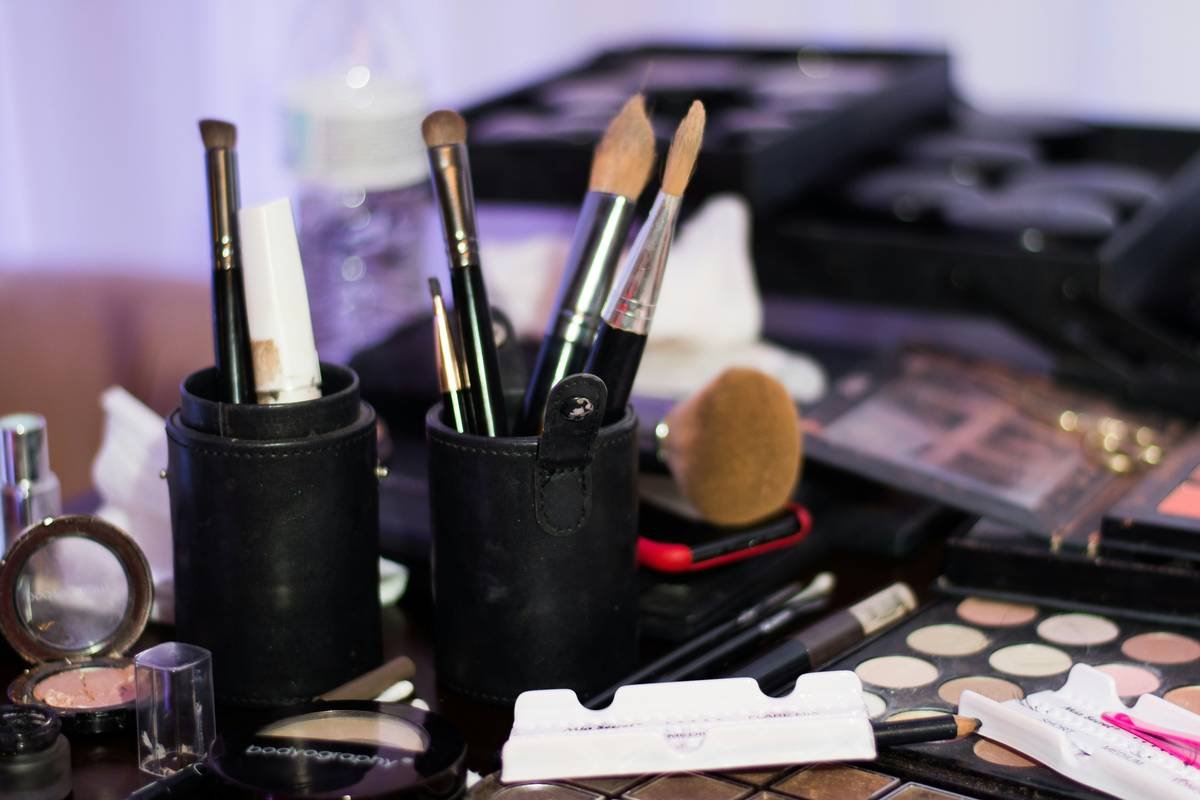 Side-by-side comparison: left shows messy makeup drawer with spilled powders and tangled brushes; right shows clean vanity with a tiered acrylic beauty organizer stand holding brushes, compacts, and serums neatly arranged.
